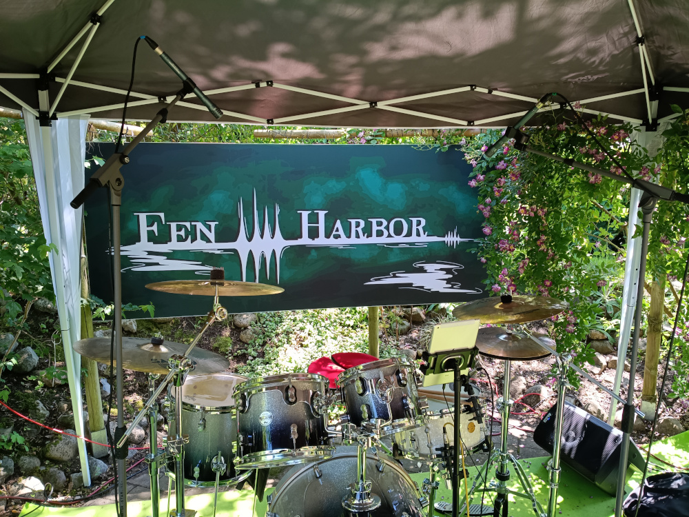 Das Schlagzeug unter dem Pavillon mit dem Band-Banner von Fen Harbor im Hintergrund